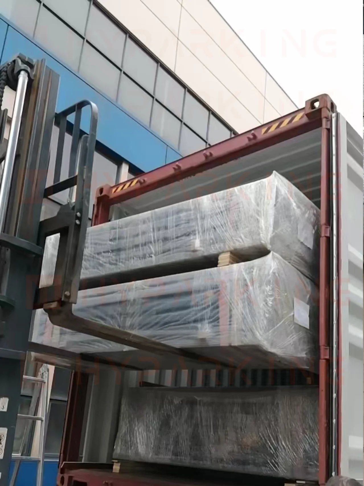 Forklift loading wrapped parking equipment pallets into a shipping container at the Shanghai factory